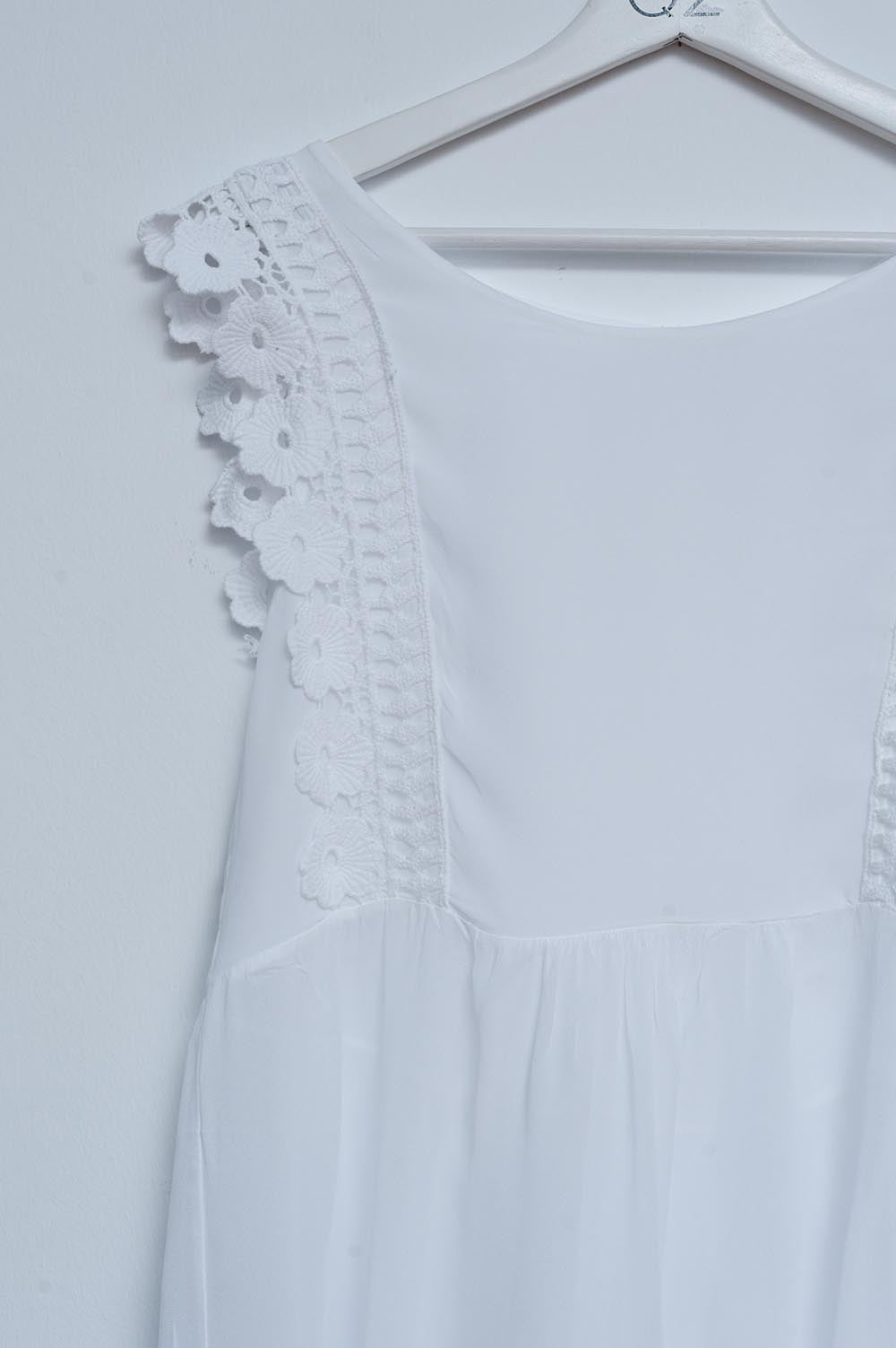 Top blanco con diseño bordado y detalle de volantes